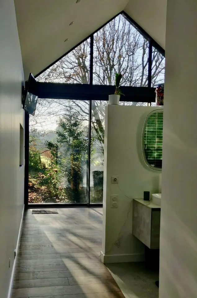 Intérieur lumineux d’une extension avec grande baie vitrée sous une toiture à deux pans
